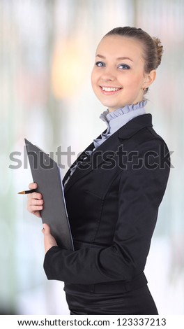 Cheerful beautiful business woman with clipboard writing