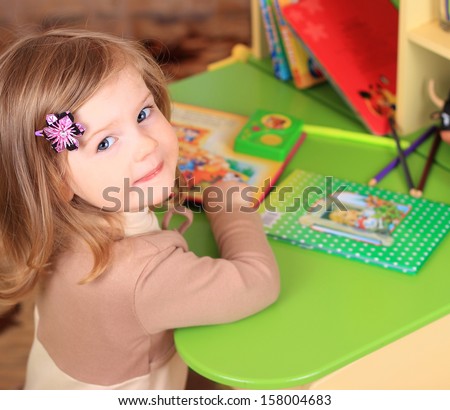 Beautiful little girl reading fairy tales at the table