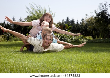 Family playing airplane on grass