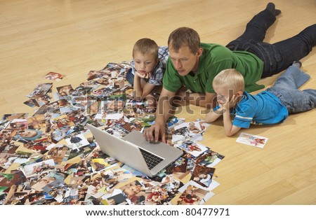 Family watching laptop on the floor, photos around