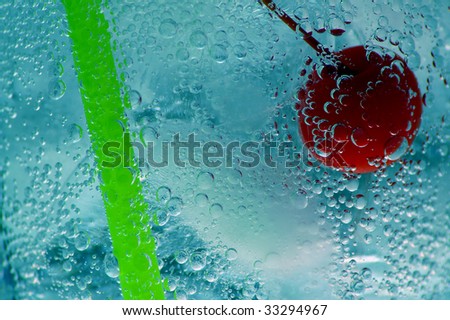 Fresh cherry, straw and ice in a carbonated beverage.