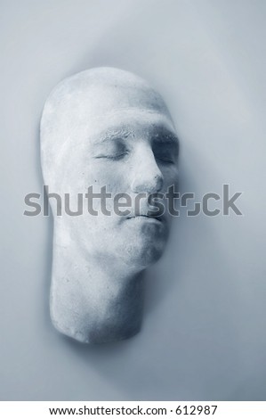 plaster face hanging on wall, abstract alone