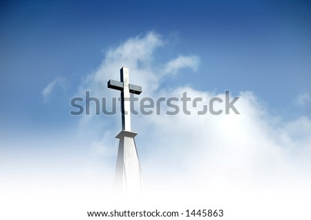 Christian cross in clouds and against blue sky