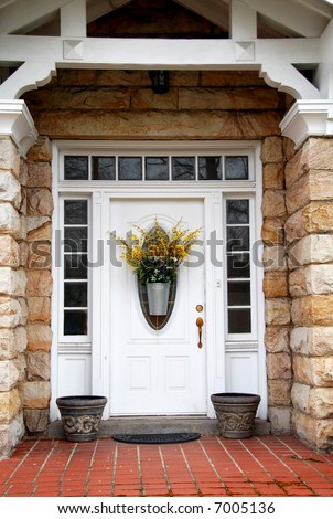 White door with transom and side lights on stone house with flower basket