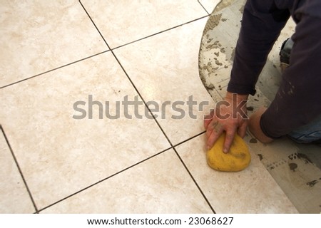 A man on his knees installing a ceramic tile floor
