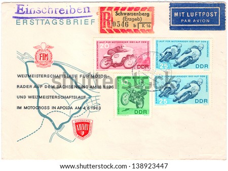 GERMANY - CIRCA 1963: An old used German Democratic Republic envelope and 4 postage stamps issued in honor of the world cup run for motorcycles showing fragments of the competition; series, circa 1963