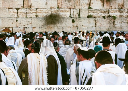JERUSALEM, ISRAEL - APRIL 5: A group of orthodox religious Jews wear prayer shawls, carry a draped Torah scroll and pray during the Jewish Pesach (Passover) celebration on April 5, 2007 at the Wailing Wall in Jerusalem, Israel.