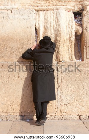 JERUSALEM - JULY 12: An religious ultra-orthodox Jew wearing a prayer shawl draped prays at the Wailing Wall in the Old City of Jerusalem, July 12, 2006.