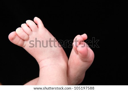 mothers hand holding babies little feet, making her hands in the shape of a heart