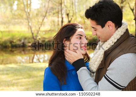 Young attractive couple who are in love spending a happy day together in the park near a river stream in winter