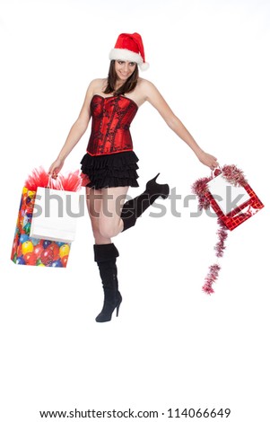 Pretty brunette woman wearing black and red celebrating Christmas by walking and skipping with shopping bags and presents isolated on white studio background