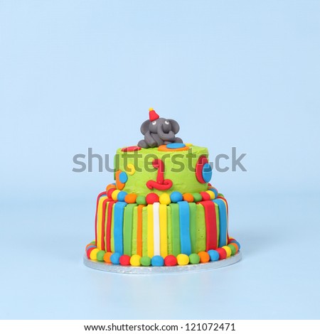 Lime green elephant cake on blue seamless background with red, blue, white and orange stripes and polka dots