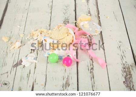 Smashed up birthday cake taken at end of party and messing the antique distressed wooden floor
