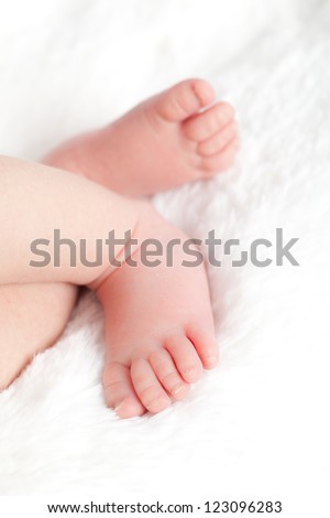 Soft and smooth baby feet resting on white fluffy blanket