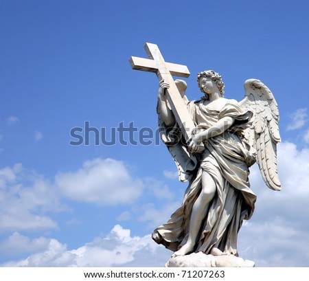 Holy statue of carved winged angel with cross in blue sky and clouds
