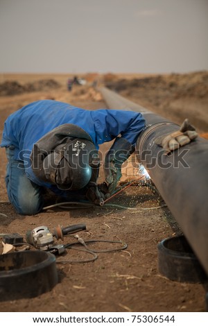 Industrial welder working on oil and gas pipeline