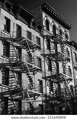 Black and white photo of the exterior of a building in New York with old fire escape.
