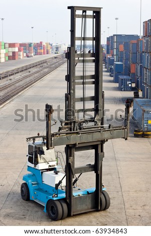 in the container storage area, we can see too much lifting crane and colorful stack under the blue sky