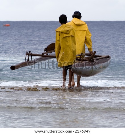 Father and son launching an outrigger canoe off the reef.  Father was going fishing for food.  Niue island