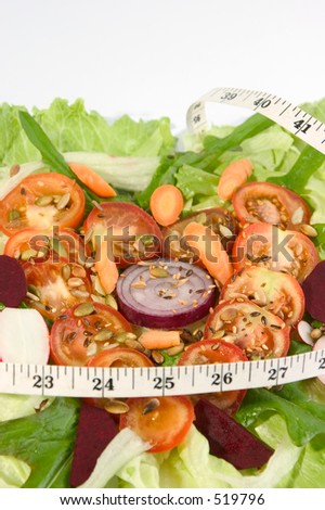 Tomato slices in heart shape on a bed of lettuce with salad vegetables, suggesting healthy eating is good for your heart
