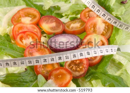tomato slices on a bed of lettuce with a metric tape measure suggesting healthy weight controlled diet