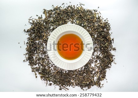 White cup of tea with dried tea leaf on the white background
