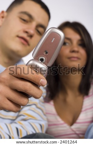 Man and woman looking at the mobile phone\'s screen.  Focus on the mobile. Faces unfocus.