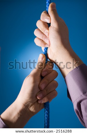 Man's hands holding blue rope. Blue background in studio.