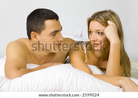 Young couple in the bed. Man's holding woman. They're looking their faces.