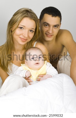 Young parents and their newborn son in the bed.