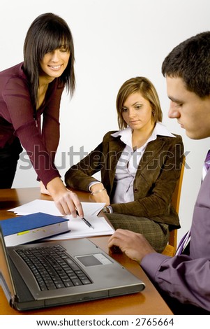 Women and a man having conversation at conference\'s table. Standing woman\'s  showing something on the paper.