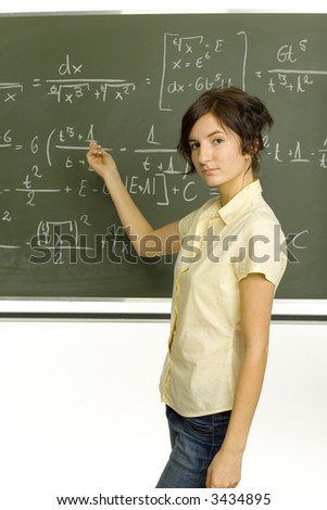 Teenage girl standing in classroom. Showing exercise on blackboard. Looking at camera. Side view