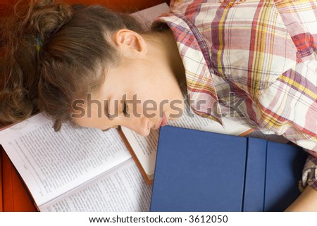 Young, beautiful woman sleeping on orange couch on books. Holding books. Orange background