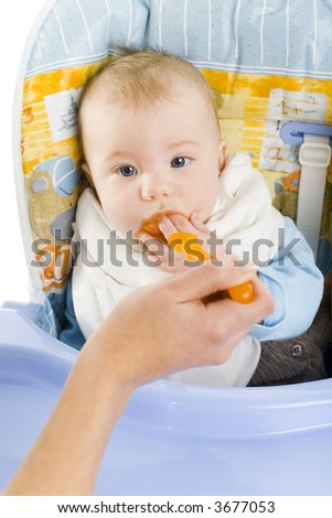 Hand of young woman with baby. Baby is sitting on baby\'s chair. Mother is feeding him. White background