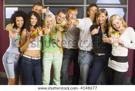Large group of teenagers during the party. Looking at camera and smiling. Girls holding drinks. Everybody holding thumbs up