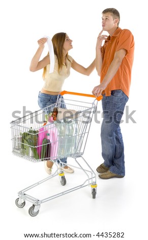 Young couple with trolley. Discussing about shop bill. Boy thinking about something and smiling, girl is angry. Isolated on white in studio, whole body