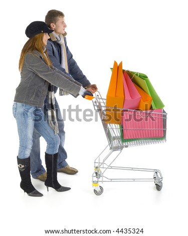 Young couple with full trolley. Smiling and looking straight. Isolated on white in studio. Whole body, side view