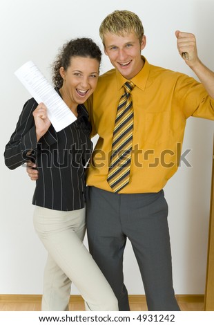 Young, happy business couple. Man is holding keys, woman is holding  some kind of contract. Looking at camera, front view