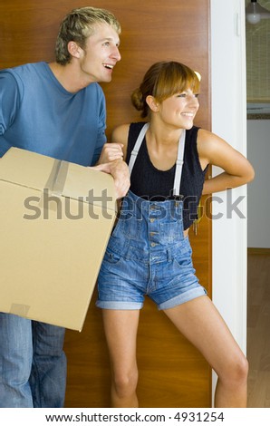 Young couple getting in to new flat. They\'re looking happy and surprised. Man is holding box