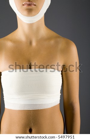 Young, unhappy woman with bandage on head and breast. Front view, gray backgroun