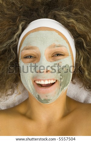 Young happy woman with green purifying mask. She looking at camera.