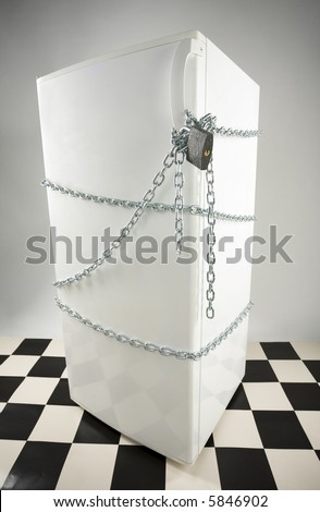 Closed fridge enwinded by chain and lock. Grey background. High angle view