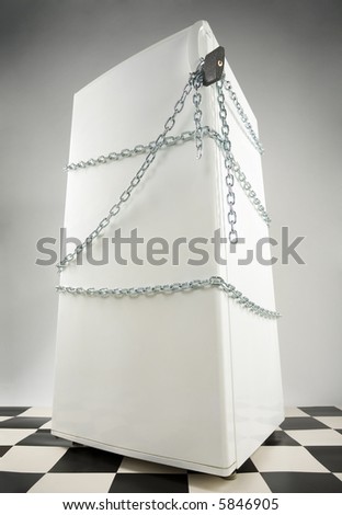 Closed fridge enwinded by chain and lock. Grey background. Low angle view