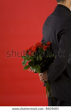 Businessman holding bouquet of roses behind his back. We don't see his face. Side view
