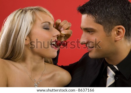Young enamoured couple. Man is feeding woman by cherry and smiling