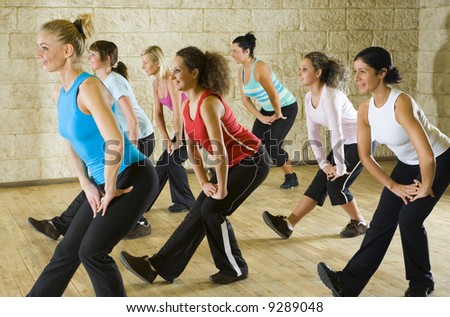 A group of women exercising in the fitness club. Focus on the woman in red shirt. Side view.