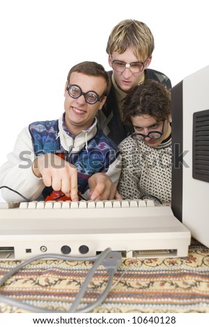 Three nerdy guys sitting in front of old-fashioned computer. One of them is pushing the button on keyboard and looking at camera. front view, white background