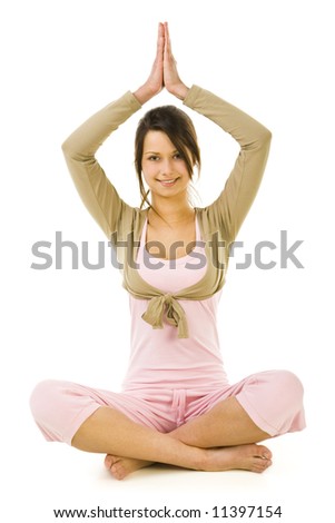 Young woman sitting cross-legged with hands over head during exercises of yoga. Looking at camera and smiling. Whole body. Front view. White background.