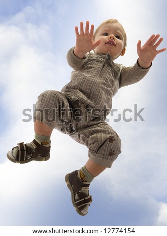 A little, blonde boy on all four. The sky background. Unusual angle view - directly below.
