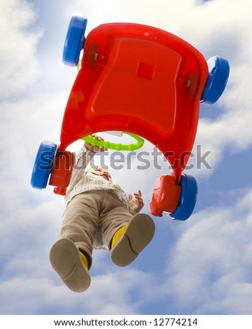 Baby boy pushing red baby cart. Isolated on white background. Unusual angle view - directly below.